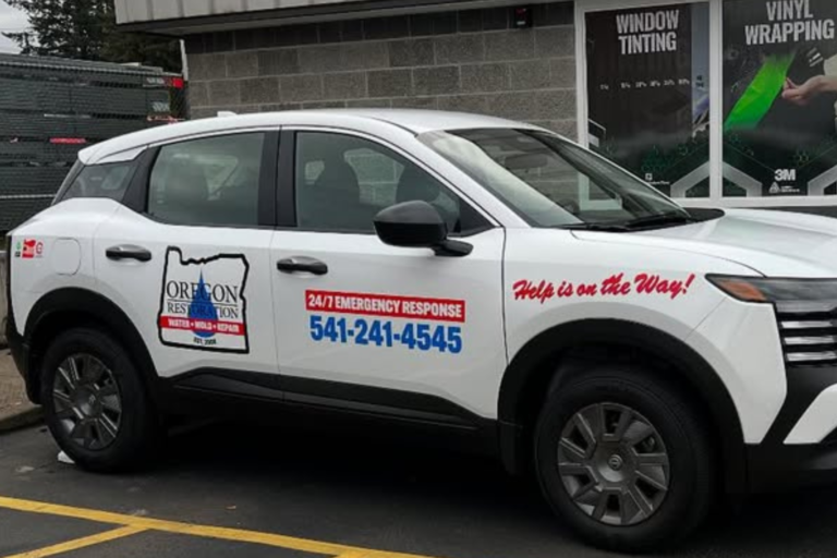 A white SUV featuring a prominent red and white logo on its side, parked in a well-lit area.