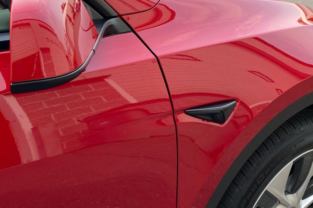 The rear view of a red Tesla Model Y, showcasing its sleek design and modern features.